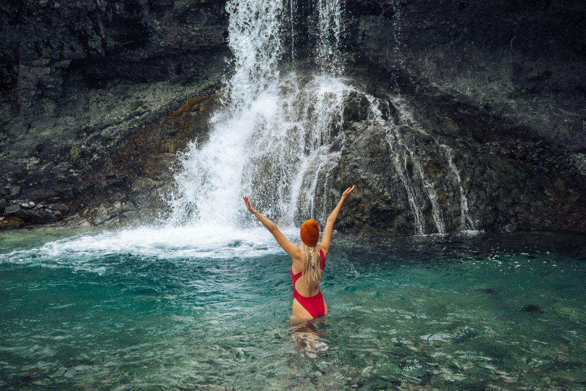 woman in the water in front of the waterfall