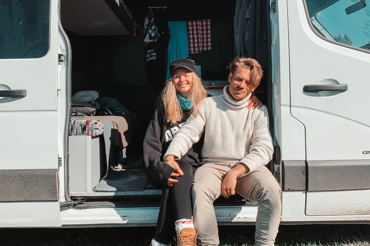 two people are sitting inside a campervan and smiling