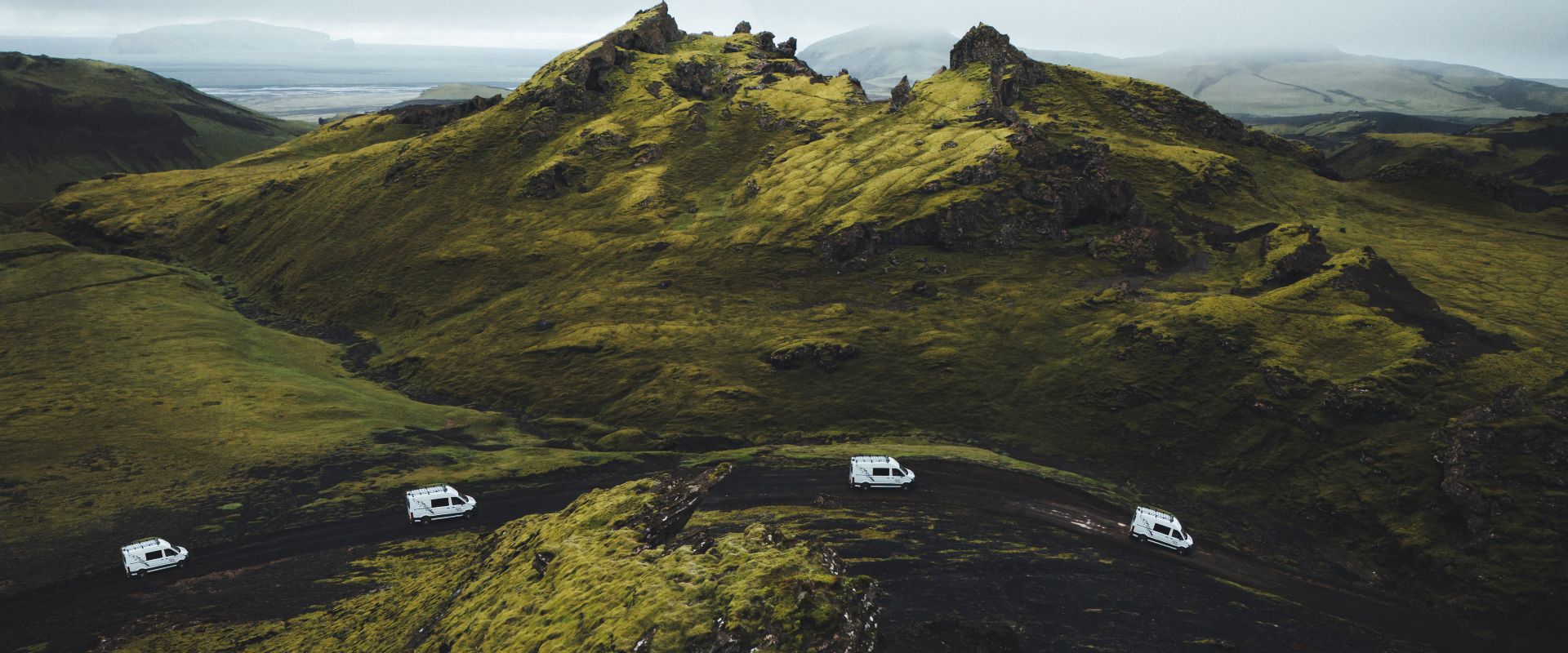 Four vans driving on a gravel road