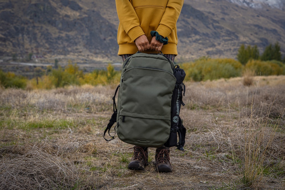 A person is holding a dark green backpack