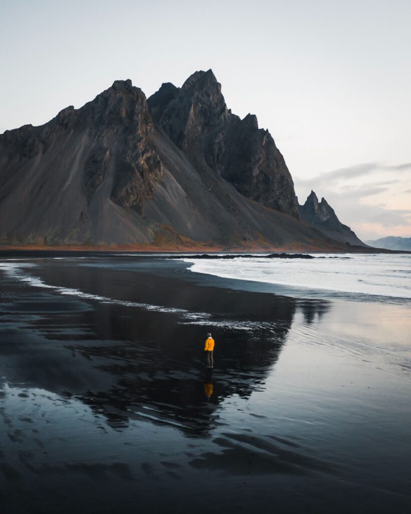 Alone man standing on a black sand beach in Iceland