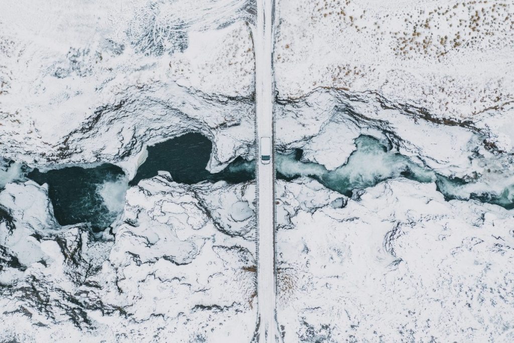 Overhead view of a car driving over a bridge in winter