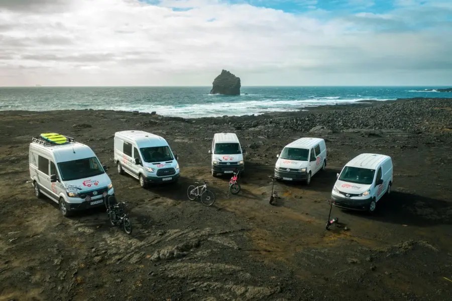 Five campervans parked on the beach with a beautiful ocean view.