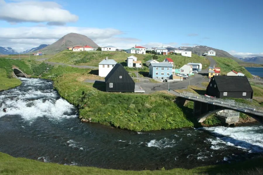 small Icelandic town located on a river with a small bridge.