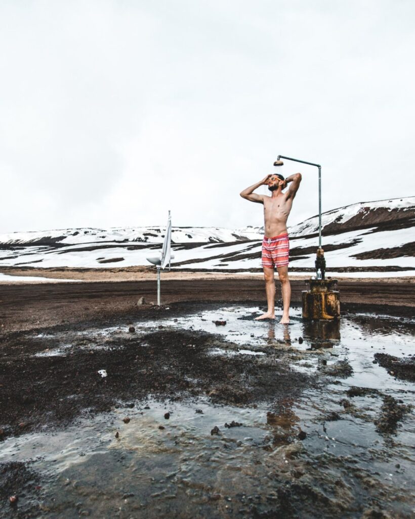 Man showering outside in Iceland in winter traveling in a campervan iceland