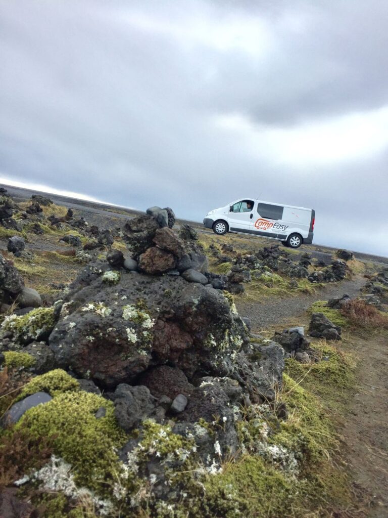 Cairn in the wilderness with a camper van in the background