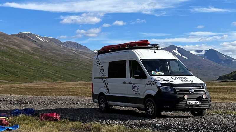 Campervan parked on the gravel road surrounded by Highlands