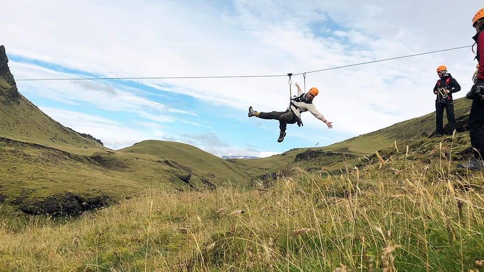 man zipping above the meadow and mountains