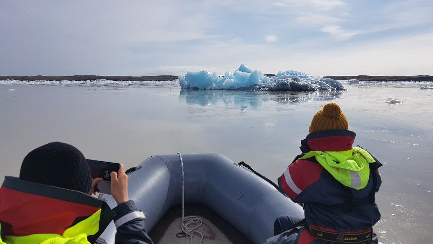 2 people in a boat taking a picture of Fjallsárlón Glacier Lagoon