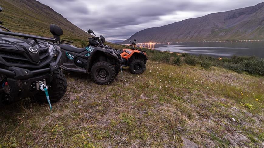 3 ATV on field. There are the mountains, bay and IOsafjordur in the background