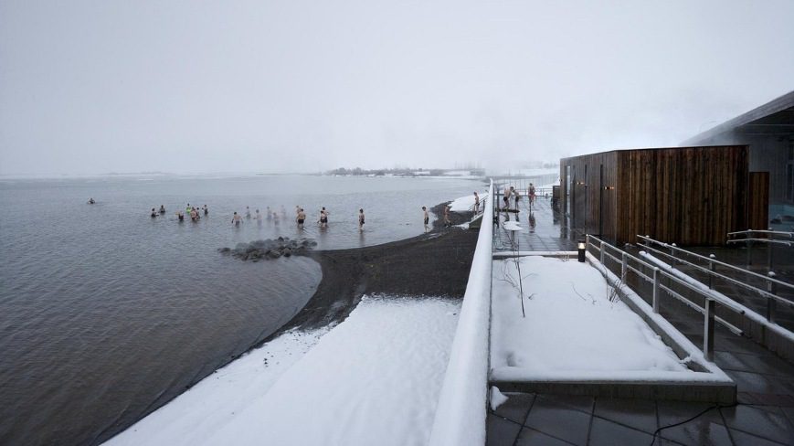People entering to the hot geothermal lake in winter scenery