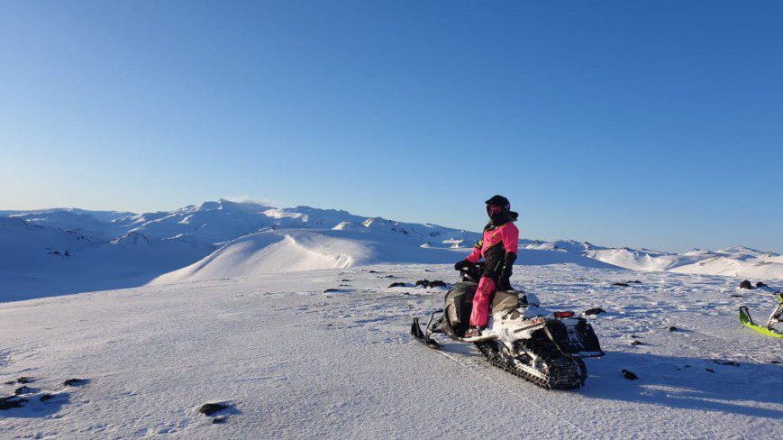 Person on snowmobile is watching snowy mountains