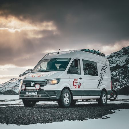 A big camper van with mountains in the background