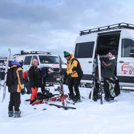 Group of people are preparing to skiing in front of campervans