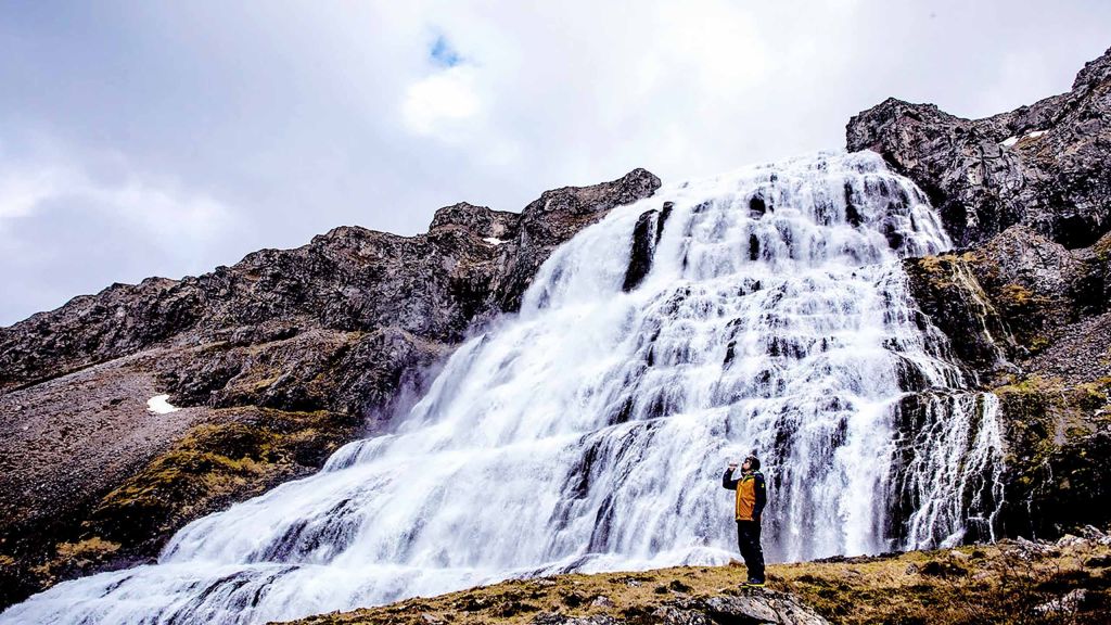 a man standing in front of a waterfall