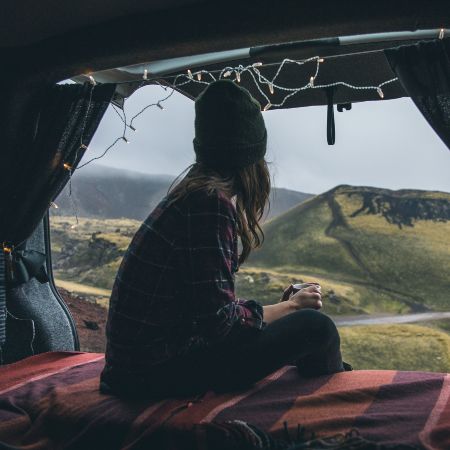 A women is sitting inside the campervan and looking at the Icelandic nature
