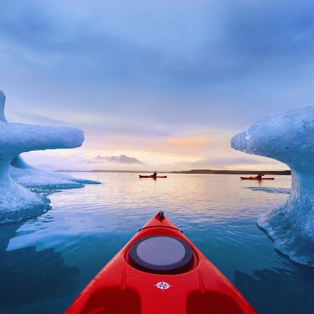 A front of the kayak surrounded by icebergs