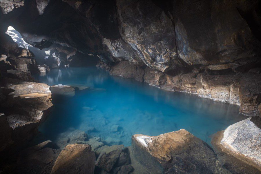 A small cave with a hidden, hot spring inside with crystal blue water.