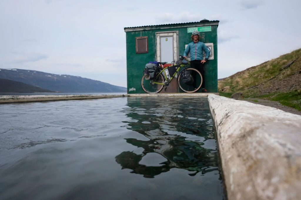 Man and bike in front of a hotpot in Iceland.