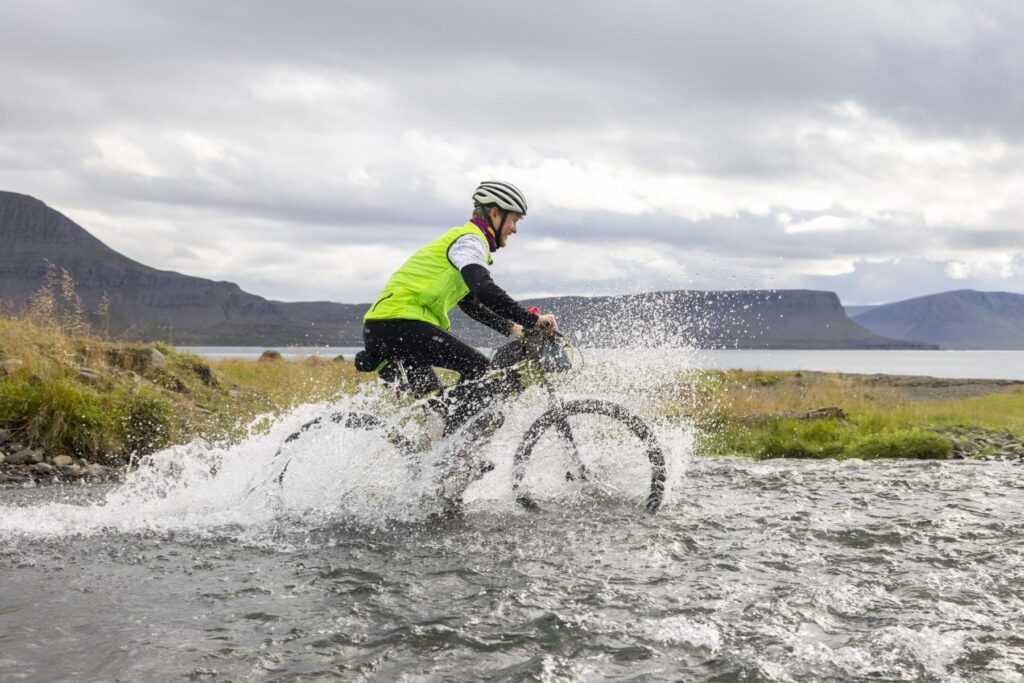 Man biking through river, Westfjords Way