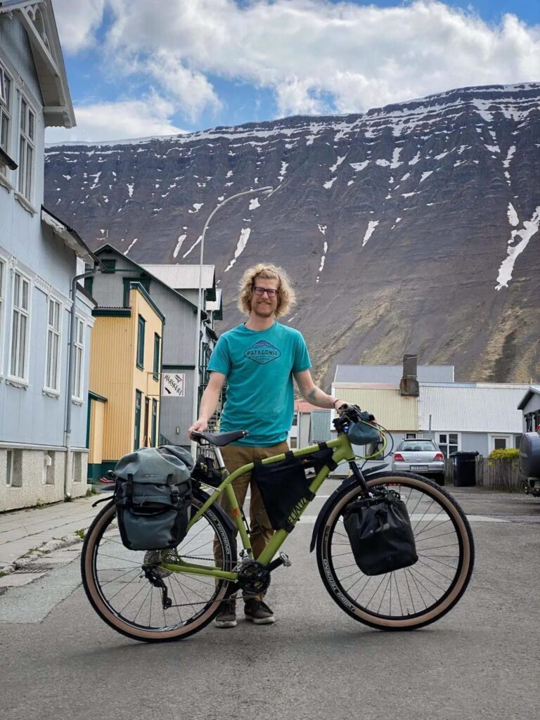 Man in front of his bike, mountains in the back.