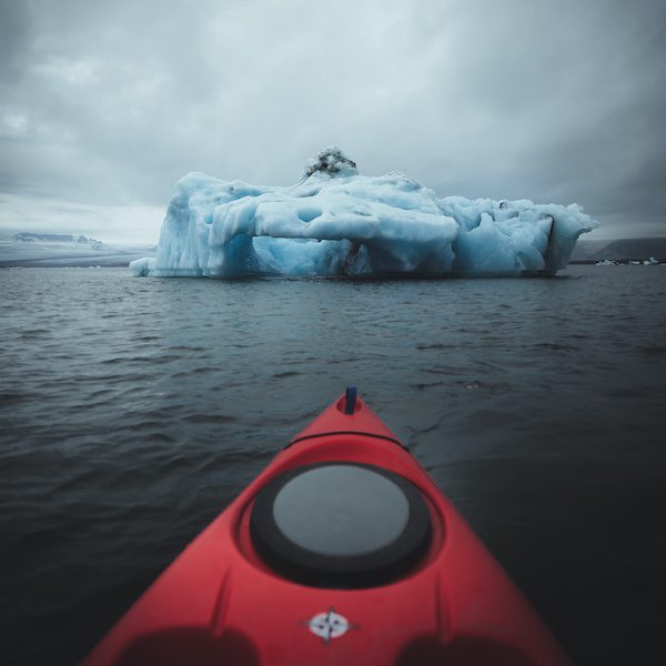 Front of kayak in the water next to the icebergs