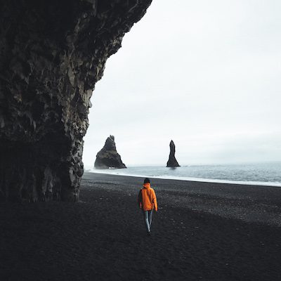 A person is walking on the black san beach