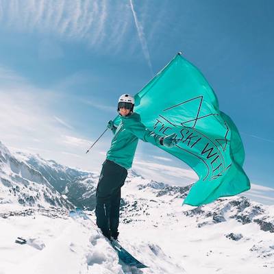A man on snowboard with green flag in a hand