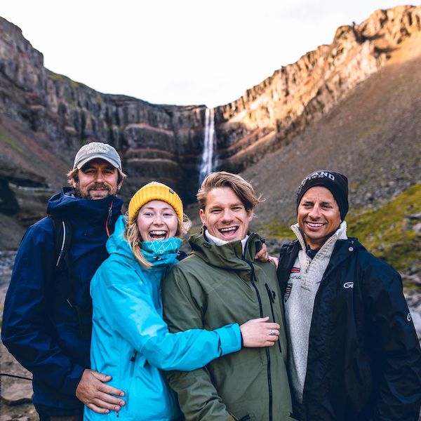 4 people are smiling and posing in front of waterfall