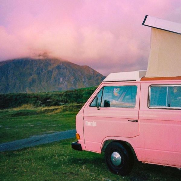 A pink vintage campervan parked on the grass