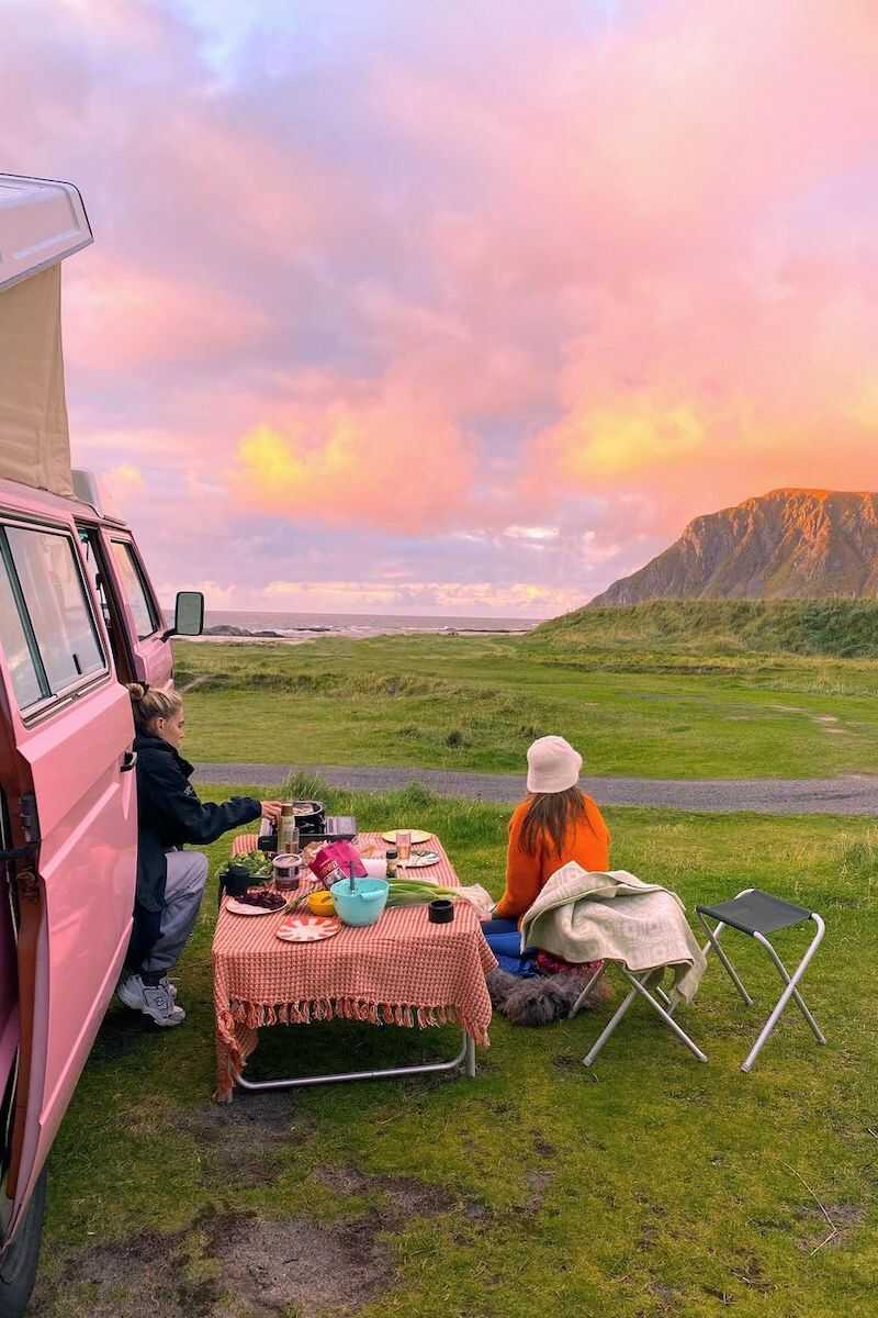 Two women are sitting and having the meal next to the campervan