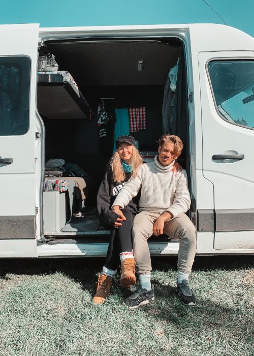 two people are sitting inside a campervan and smiling