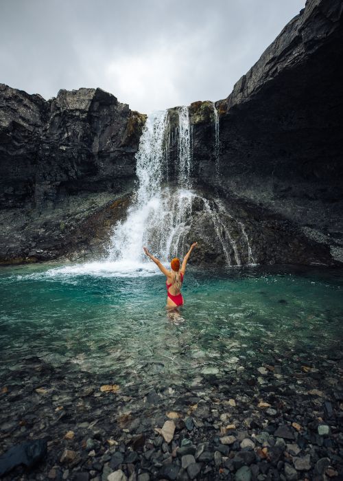 woman in the water in front of the waterfall
