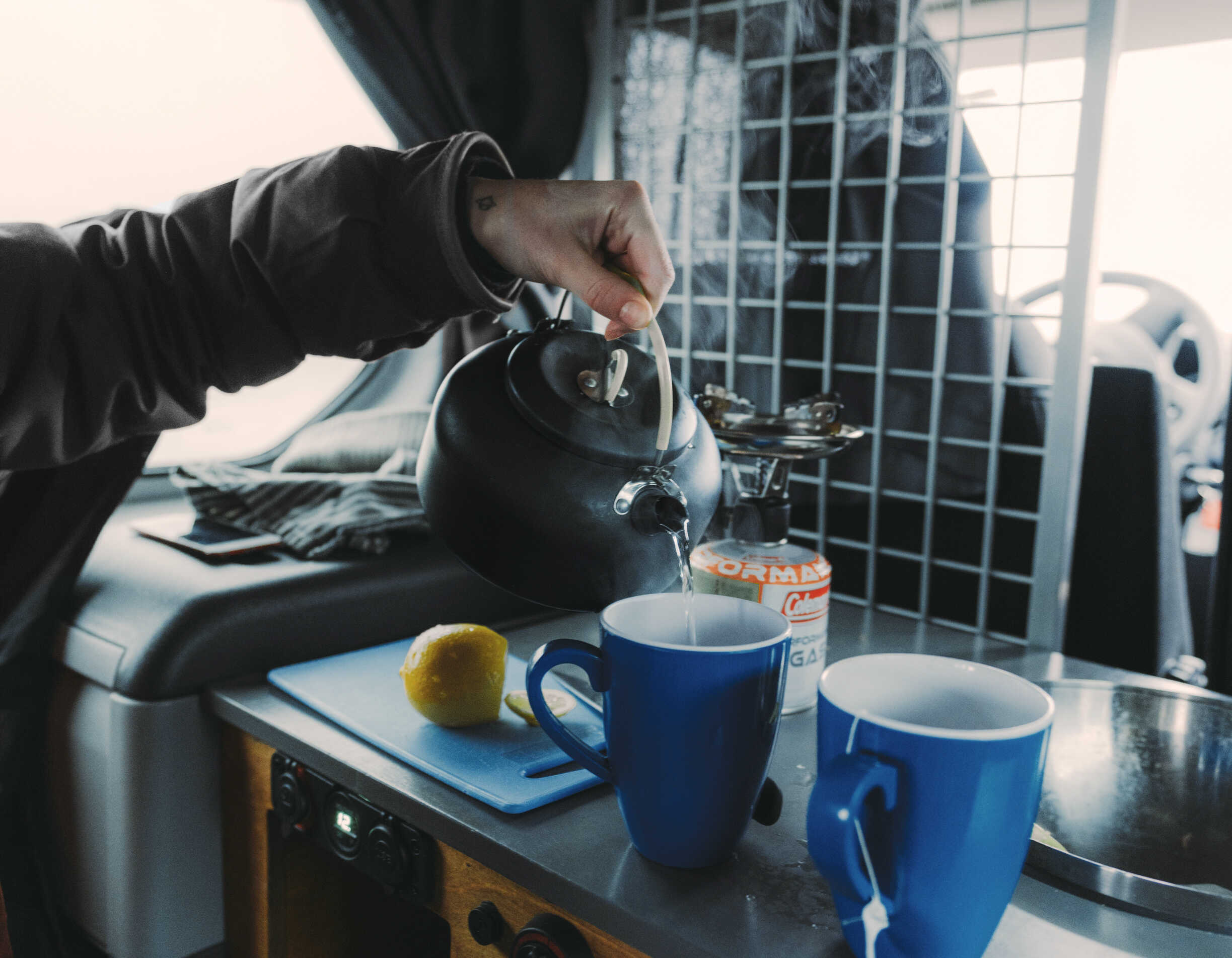 A person is making a tea inside the campervan