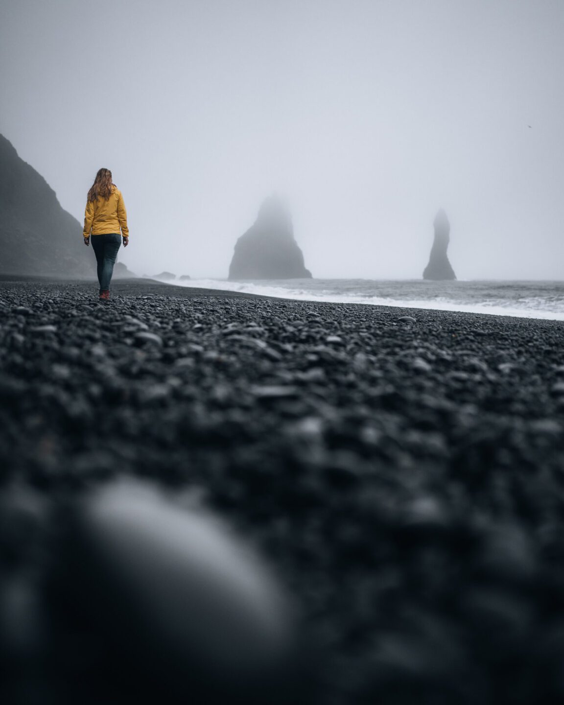 Woman is walking on the black sand beach