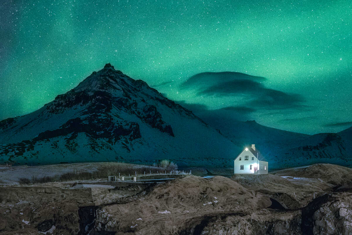 Mountain range behind the building and the northern lights on the sky