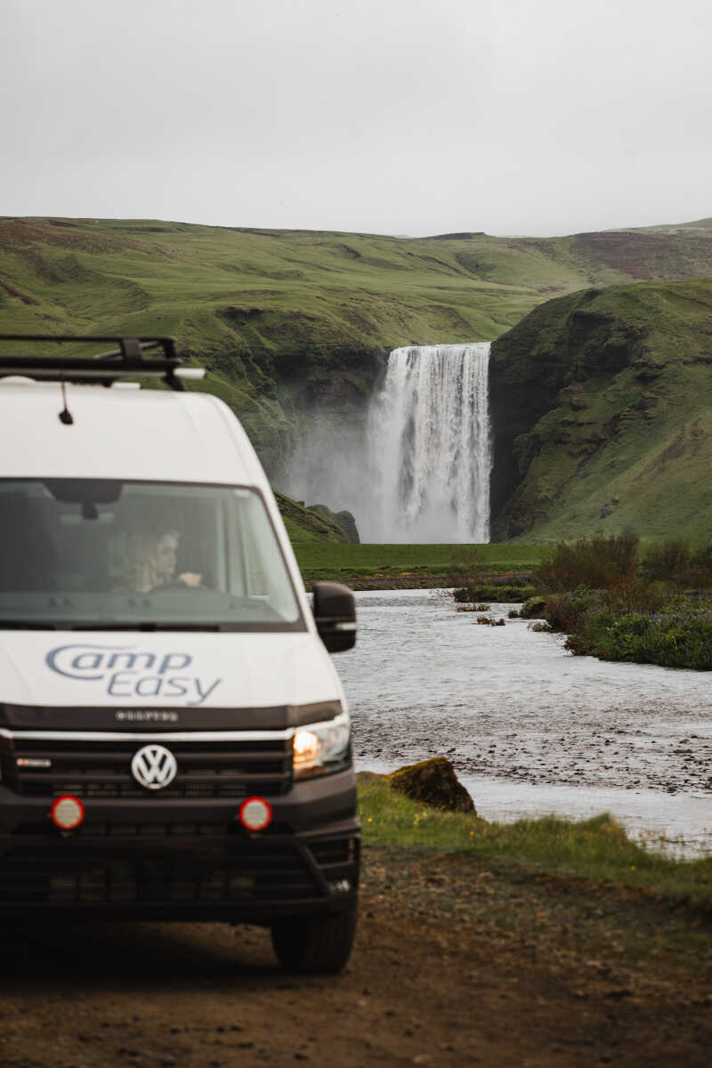 Campervan next to the river and the waterfall in the background