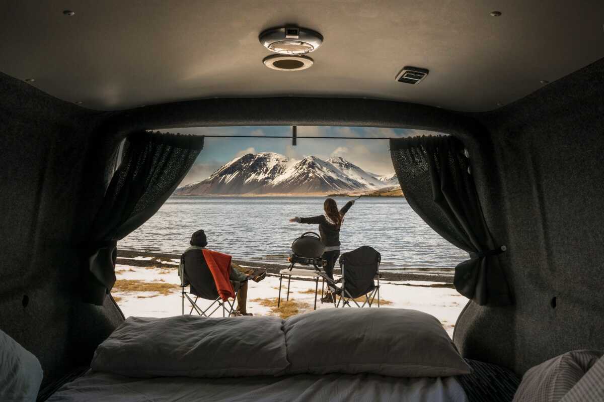 2 people sitting inside Campervan and looking at the waterfall