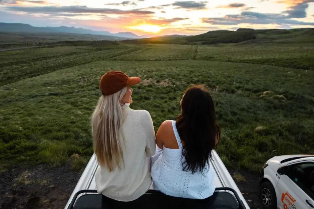 2 women sitting on the roof of the campervan