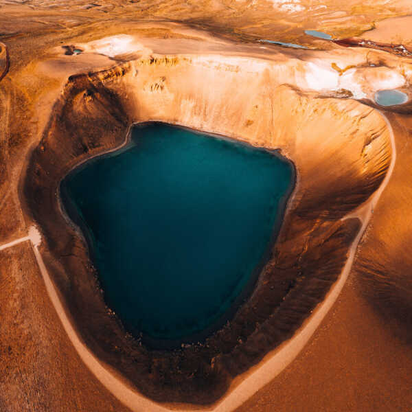 Lake inside the old volcano crater surrounded by light brown rocks