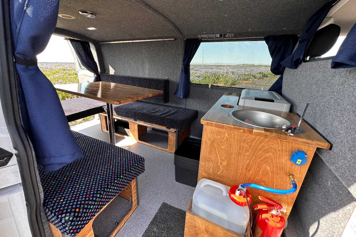 Interior view of the campervan focused on the kitchen table and dinning area