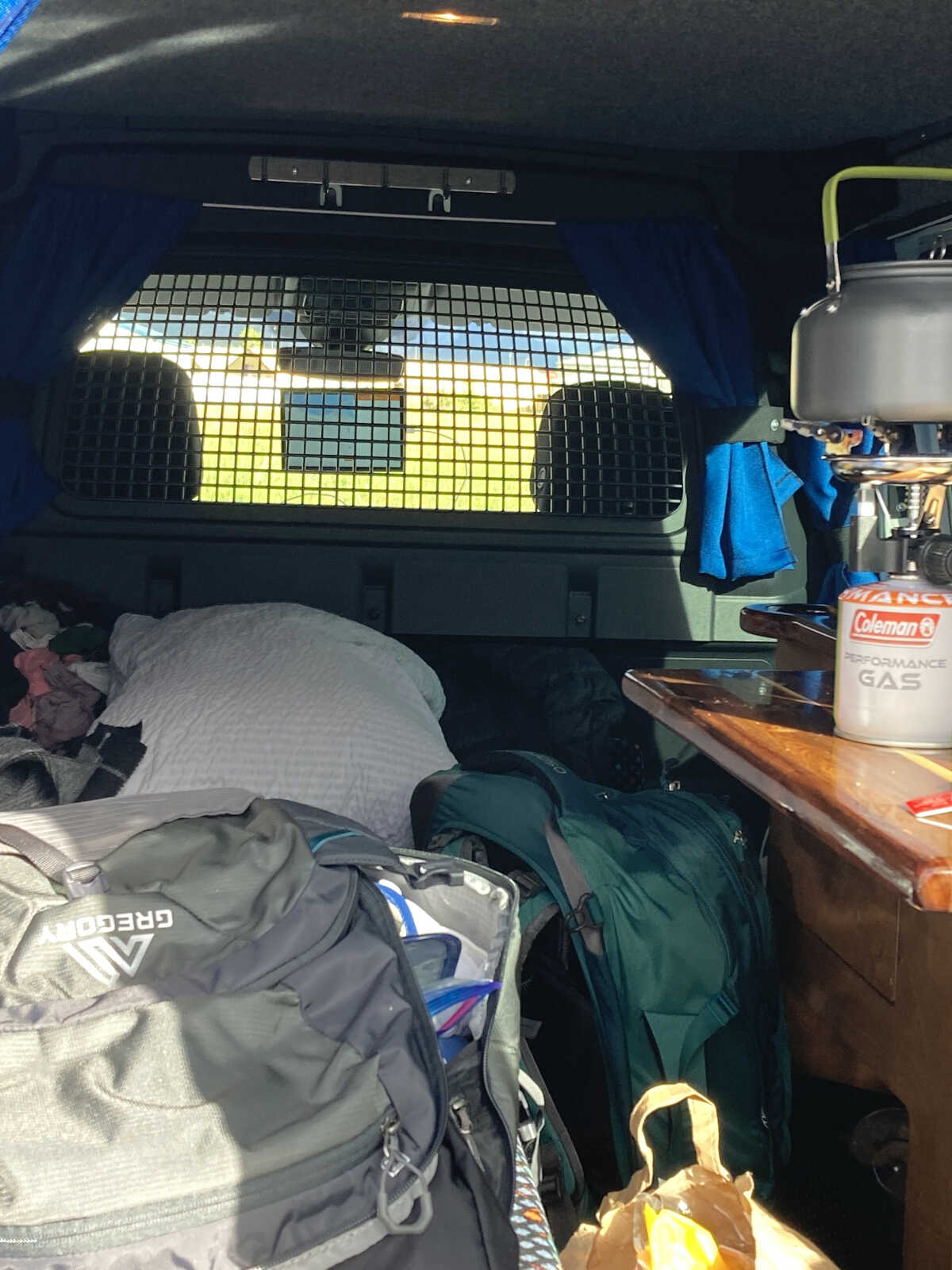 Inside view of a campervan showing a packed interior with camping gear, bags, and a cooking setup, ready for an adventure in Iceland.