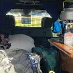 Inside view of a campervan showing a packed interior with camping gear, bags, and a cooking setup, ready for an adventure in Iceland.