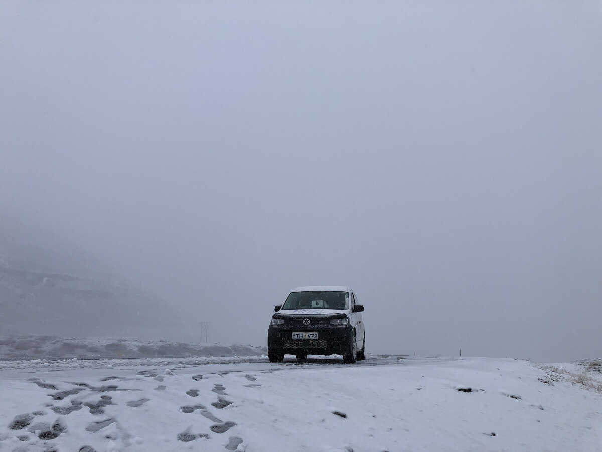 A CampEasy campervan stands isolated in a thick, snowy fog in Iceland, embodying a winter adventure in harsh yet stunning arctic conditions.