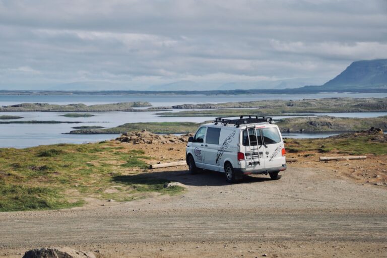 Campervan parked near a gravel road close to the water.