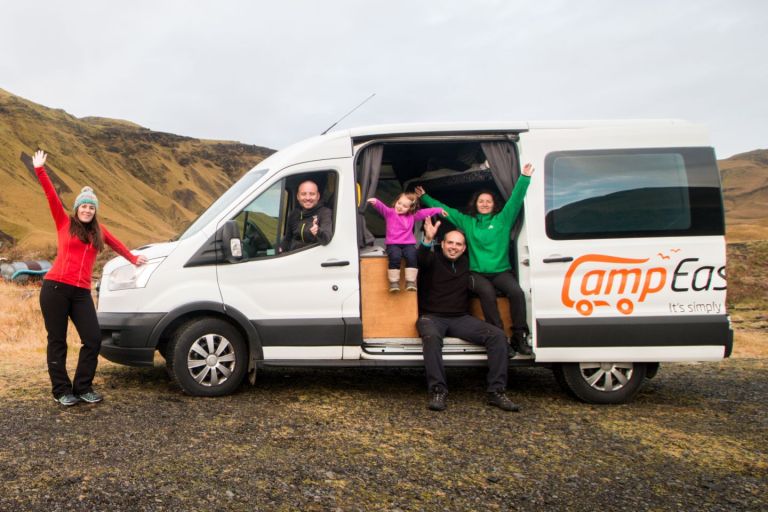 Happy family poses for a photo in front of a white camper.