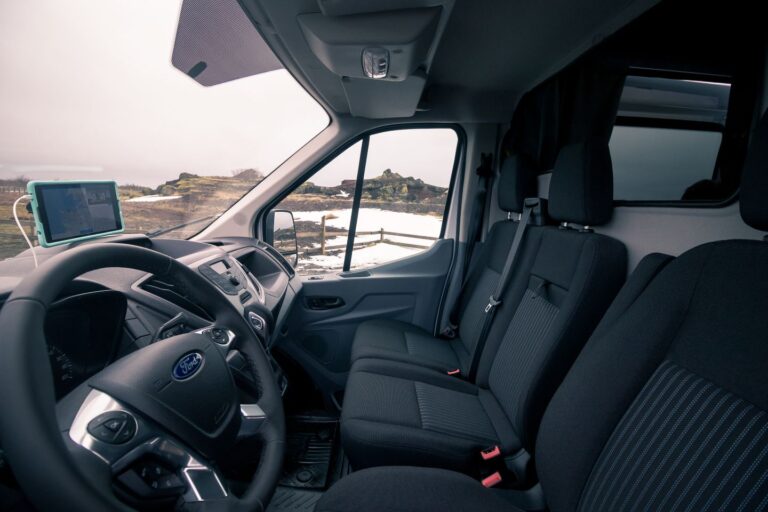 Interior view of a camping van showcasing the passenger seat and the dashboard with controls and displays.