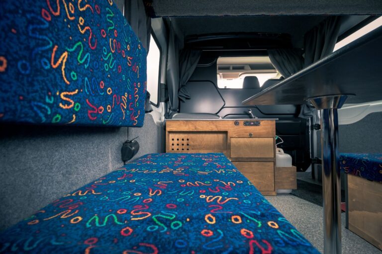 Interior view of a campervan, featuring a sitting area and a kitchen corner.