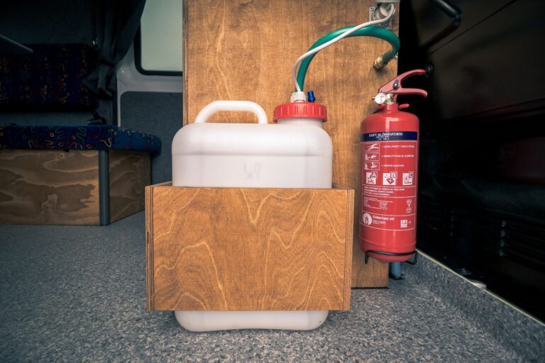 Interior view of a campervan with water tank and fire extinguisher.