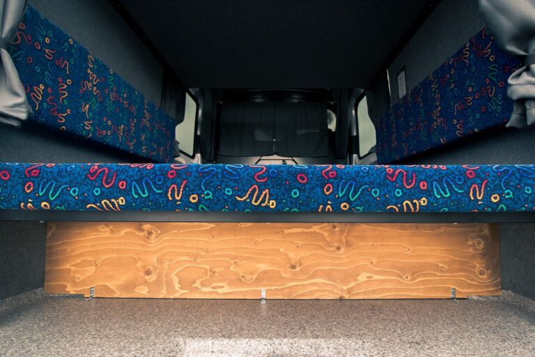 A campervan's interior view displaying a couch and bed.